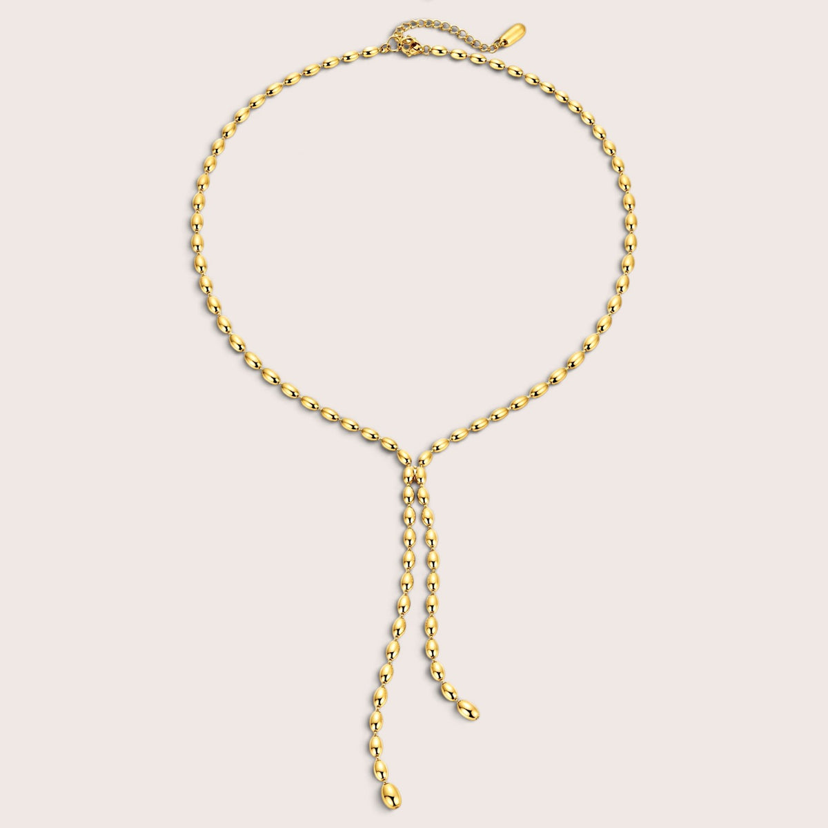 A gold chain necklace with a delicate Y-shaped drop pendant, displayed on a light beige background.