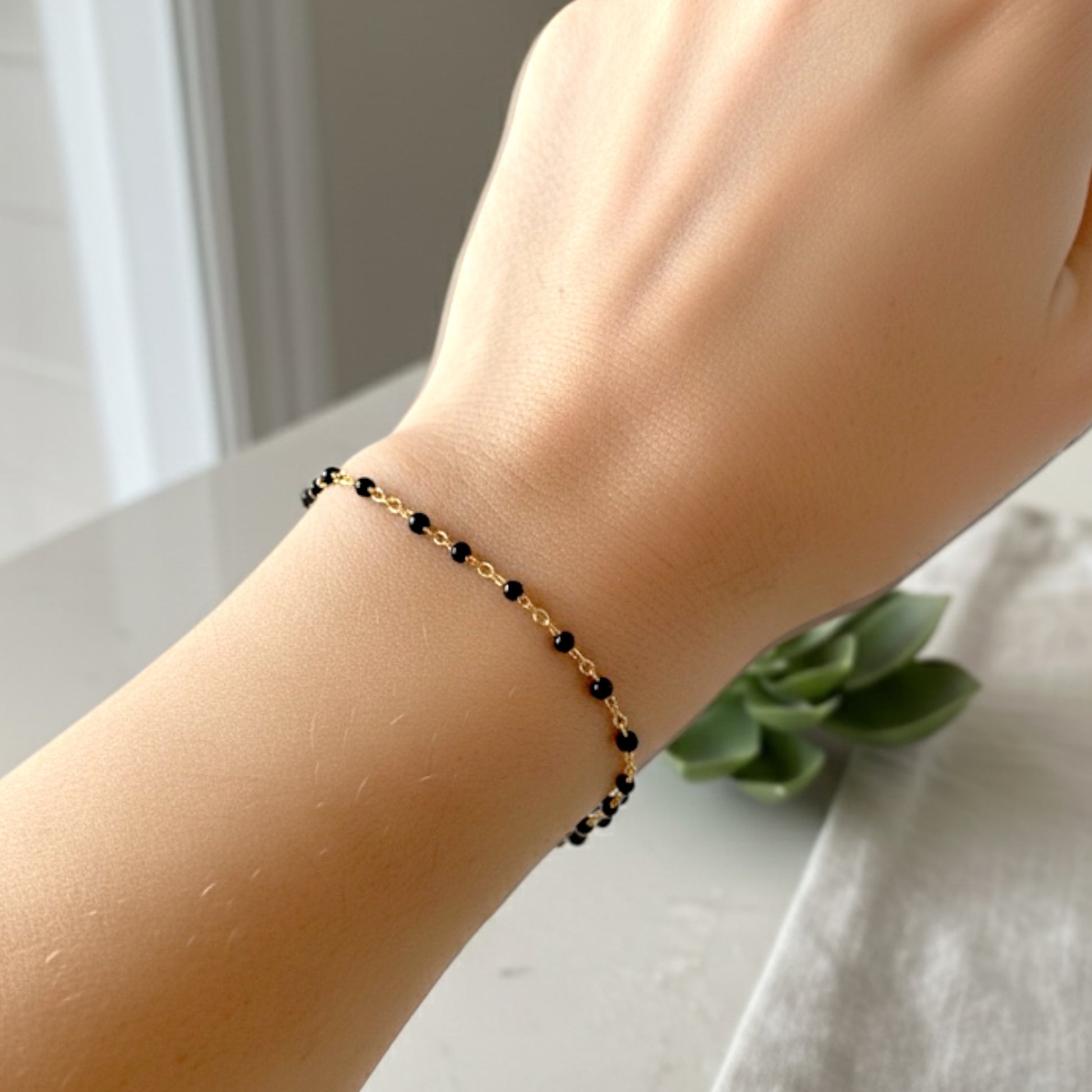 14K Gold Filled Station bracelet with black beads on a wrist