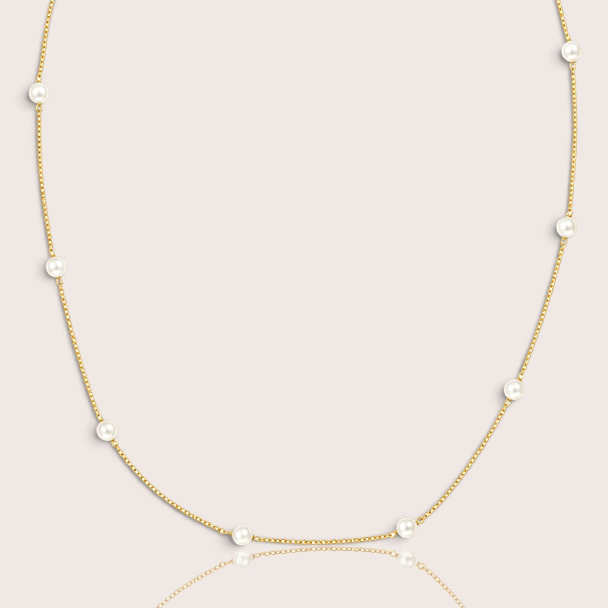 Close studio view of white pearls spaced along a fine gold-filled necklace
