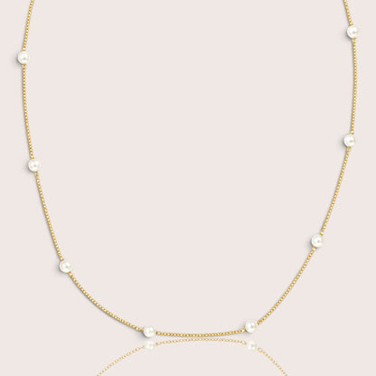 Close studio view of white pearls spaced along a fine gold-filled necklace