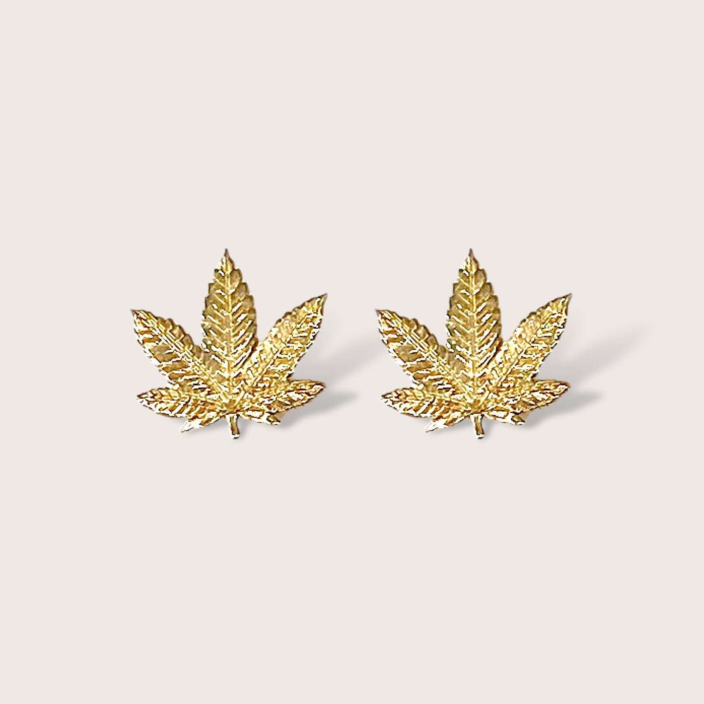 Close up front view of gold marijuana leaf stud earrings in 14K Yellow Gold