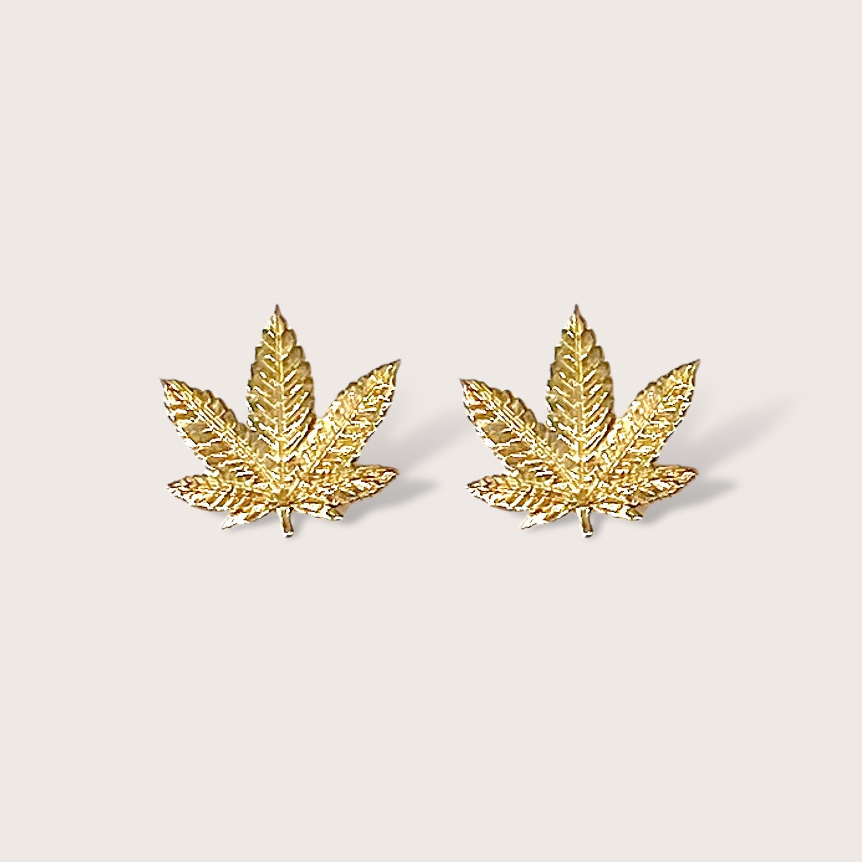 Close up front view of gold marijuana leaf stud earrings in 14K Yellow Gold