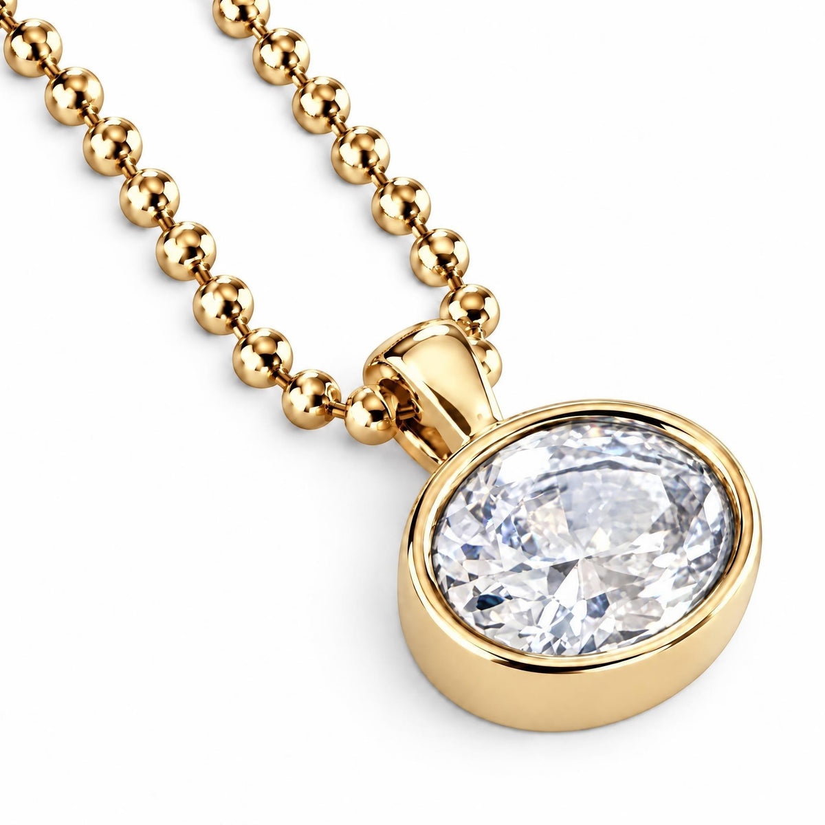 A gold ball-chain necklace with an oval bezel-set clear gemstone pendant, shown on a clean white background.