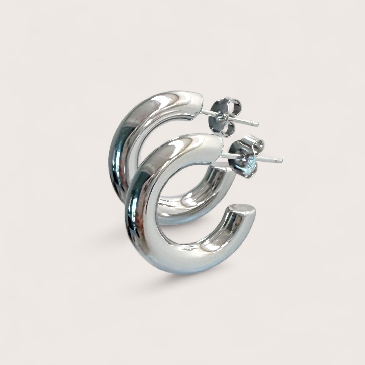 Macro angle shot of chunky silver hoop earrings in 925 sterling silver with a thick tubular design.