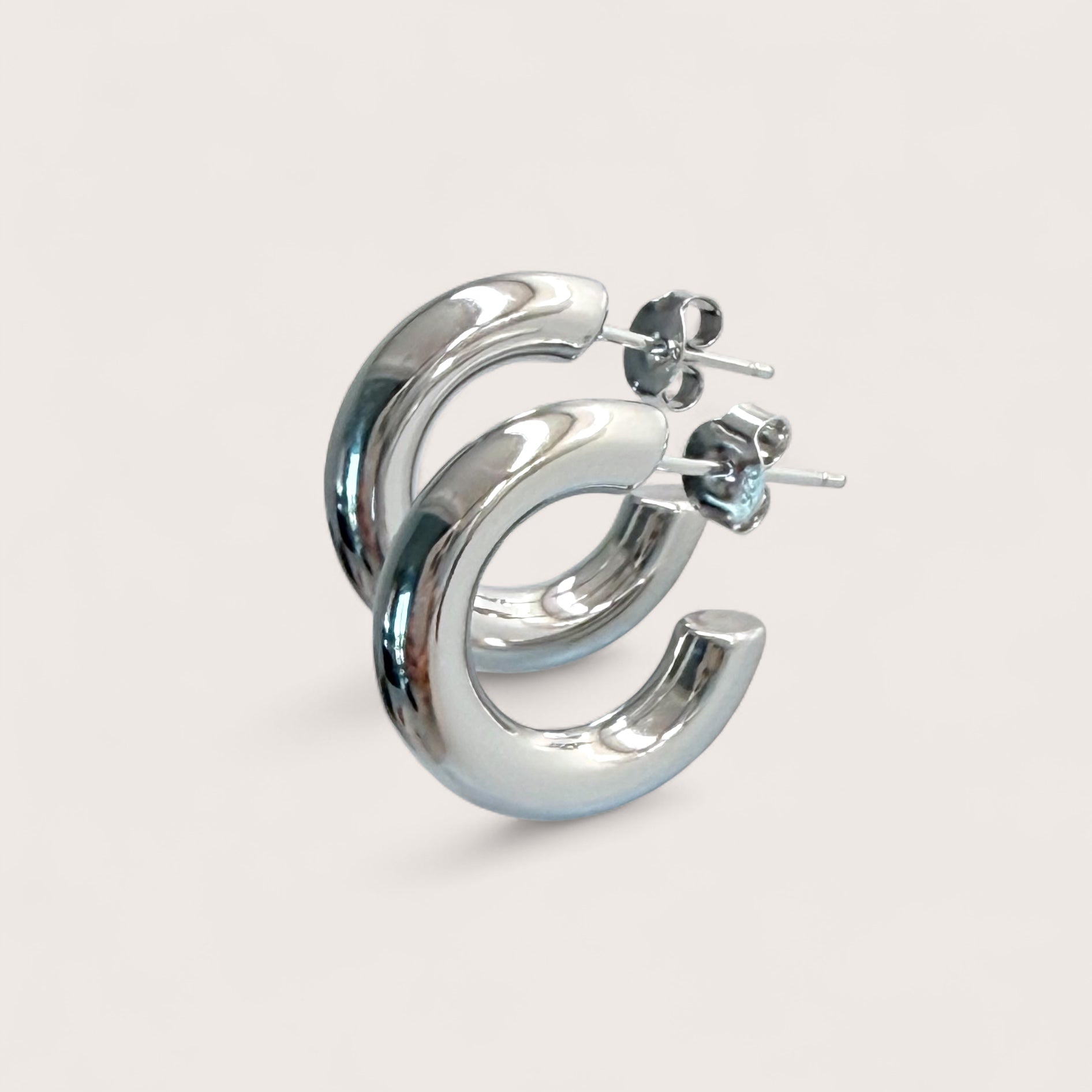Macro angle shot of chunky silver hoop earrings in 925 sterling silver with a thick tubular design.