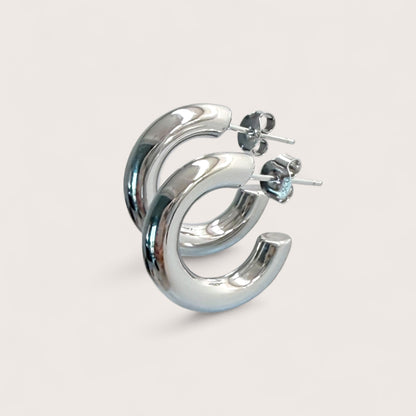 Macro angle shot of chunky silver hoop earrings in 925 sterling silver with a thick tubular design.