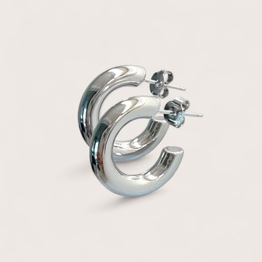 Macro angle shot of chunky silver hoop earrings in 925 sterling silver with a thick tubular design.