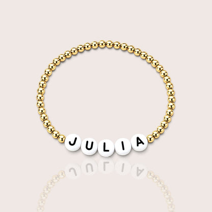 Kids personalized bracelet spelling a custom name with 14K gold-filled beads and white letter beads