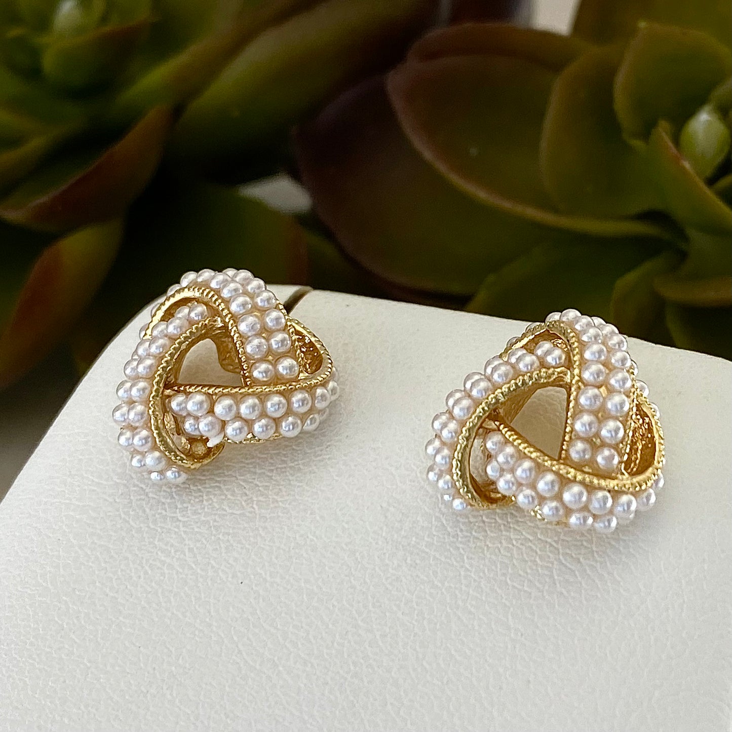 close up of 18k gold plated knot earrings with pave pearl beads