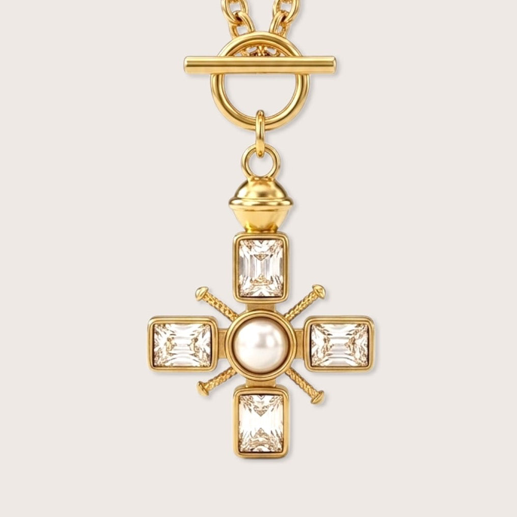 Front close up view of a waterproof PVD gold over 316L stainless steel thick cable chain necklace featuring a decorative front facing toggle clasp and a crystal-set Maltese cross pendant with a center pearl by Ashley Nicole Jewelry