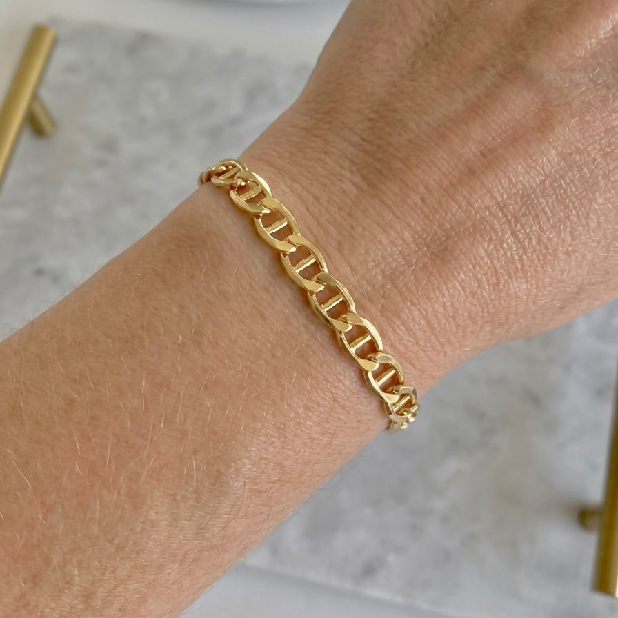 Model wearing a dainty 14k gold filled flat mariner link chain bracelet styled in a delicate everyday stack by Ashley Nicole Jewelry⁠
