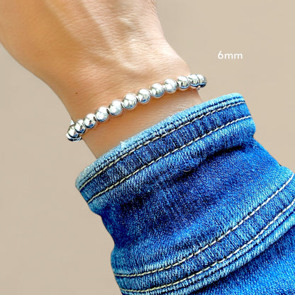 Model wearing a 6mm bracelet featuring a polished 925 sterling silver mirror polished finish and a lobster clasp by Ashley Nicole Jewelry