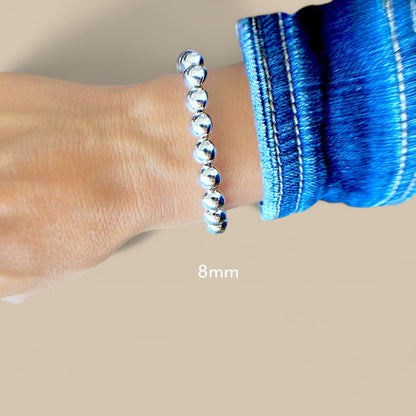 Model wearing a 8mm bracelet featuring a polished 925 sterling silver mirror polished finish and a lobster clasp by Ashley Nicole Jewelry