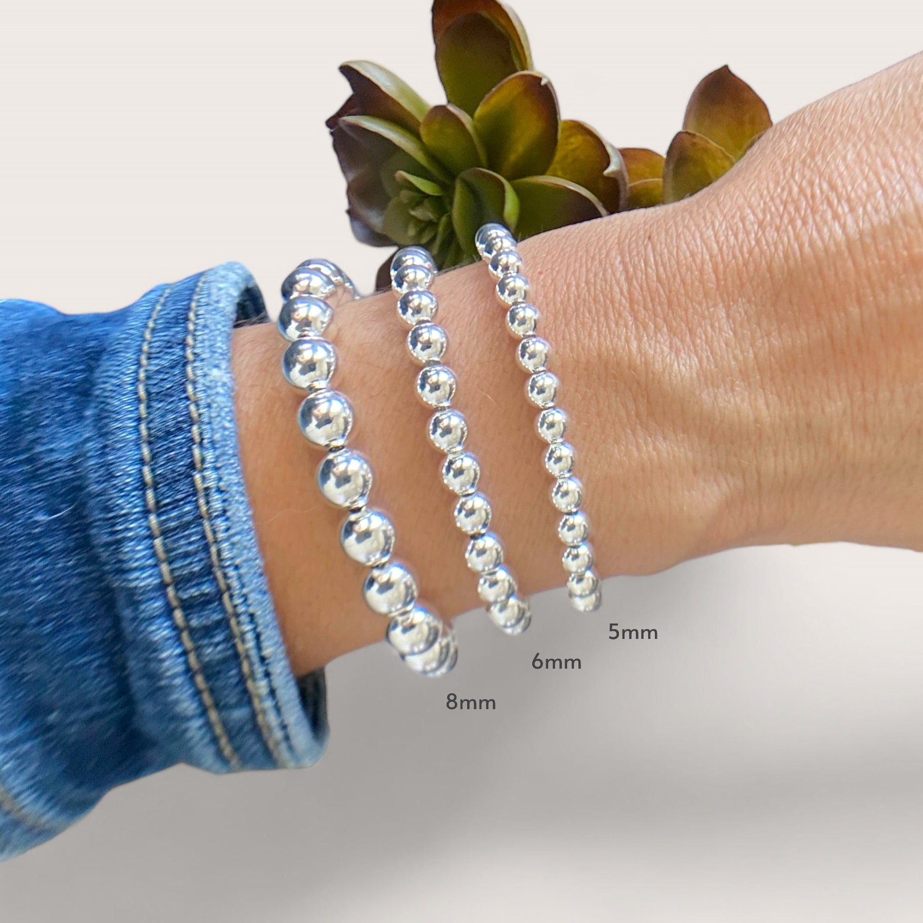 Model wearing a 5mm 6mm 8mm beaded bracelet featuring a shiny 925 sterling silver finish and a lobster clasp by Ashley Nicole Jewelry