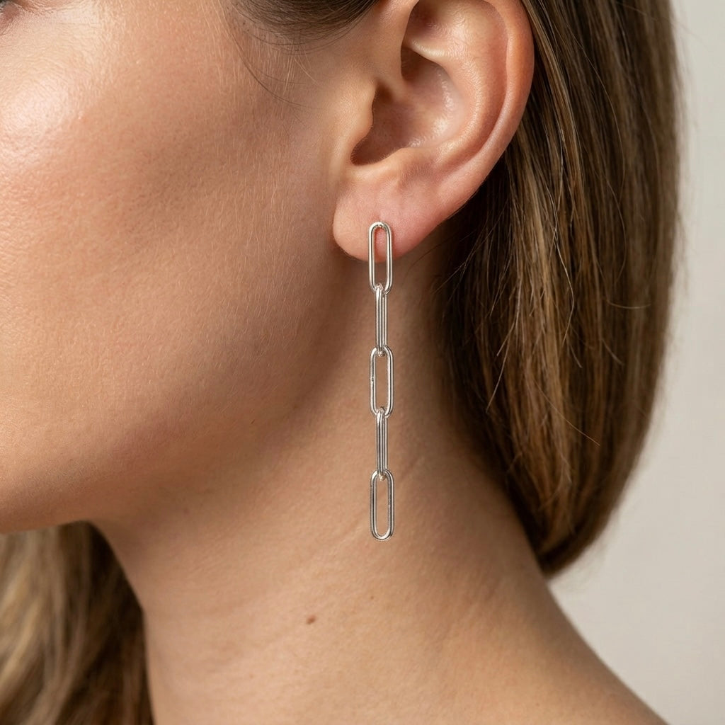A model wearing 2.5-inch paperclip chain drop earrings in bright 925 sterling silver for a clean, minimalist everyday look by Ashley Nicole Jewelry.