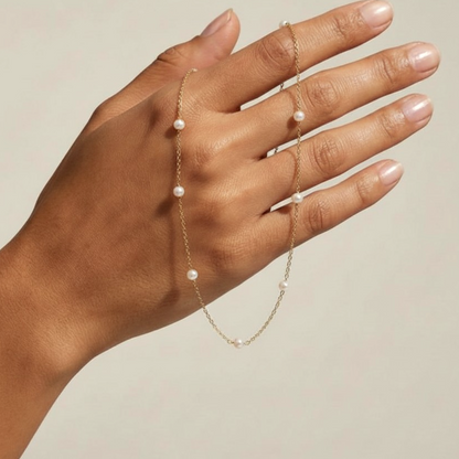 Freshwater pearl station necklace draped across a hand to show the pearl and chain scale