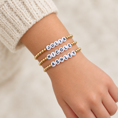 Collection of personalized kids’ bracelets with gold-filled beads and white letter beads