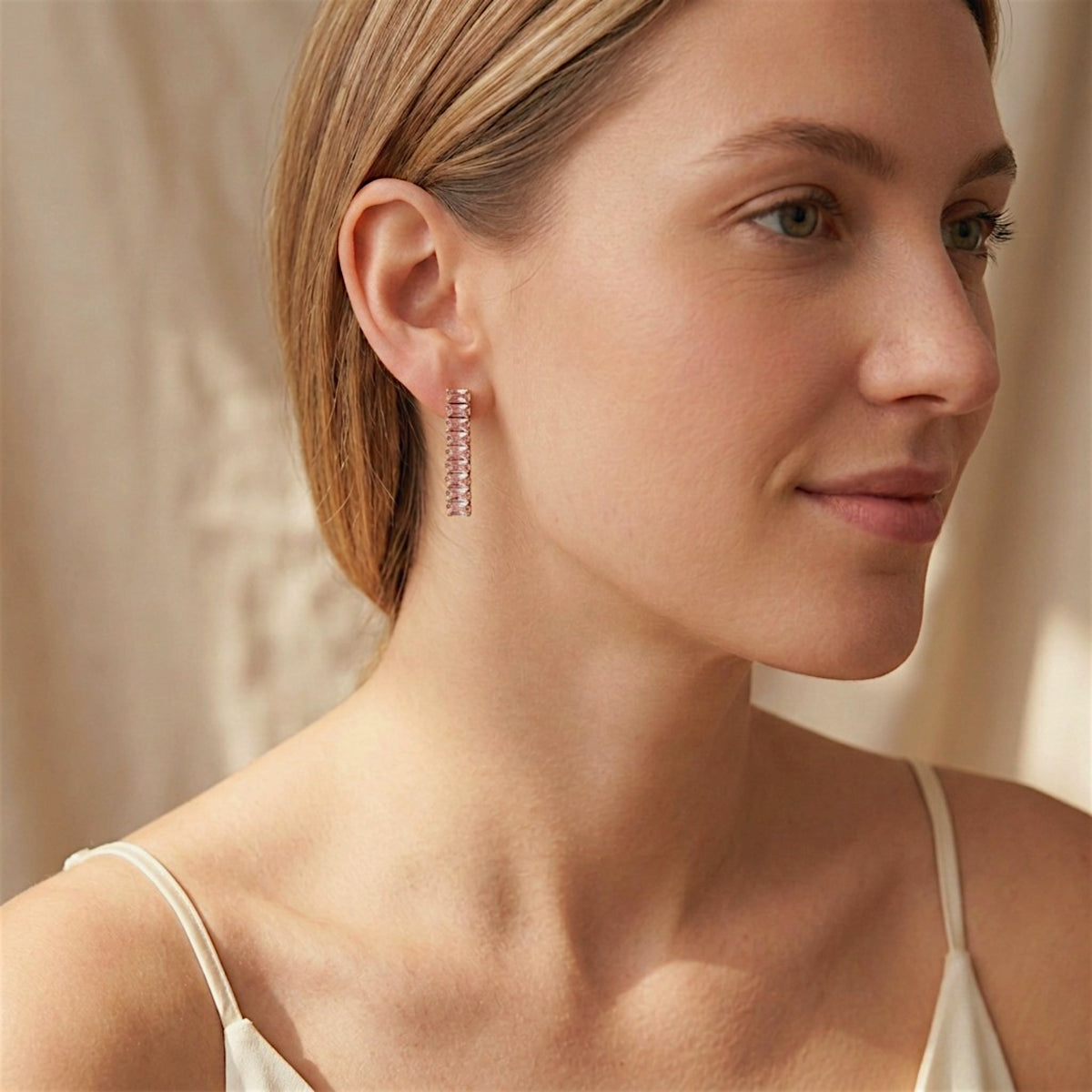 Woman wearing a pink baguette CZ drop earring with gold-tone settings and an ivory camisole.
