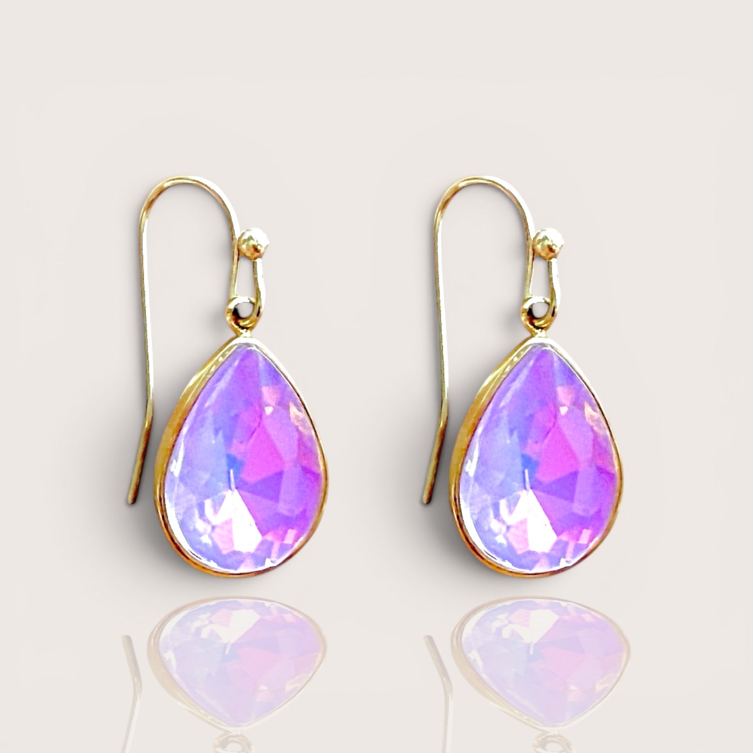Close up view of a pair of pink opalescent faceted crystal teardrop dangle earrings with 14k gold-filled French wire hooks by Ashley Nicole Jewelry