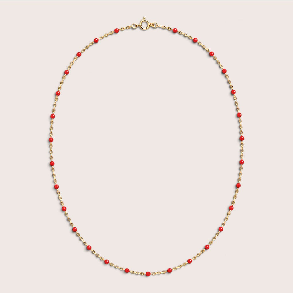 Red enamel station beads spaced along a gold-filled necklace on a light background