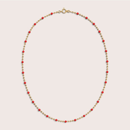 Red enamel station beads spaced along a gold-filled necklace on a light background
