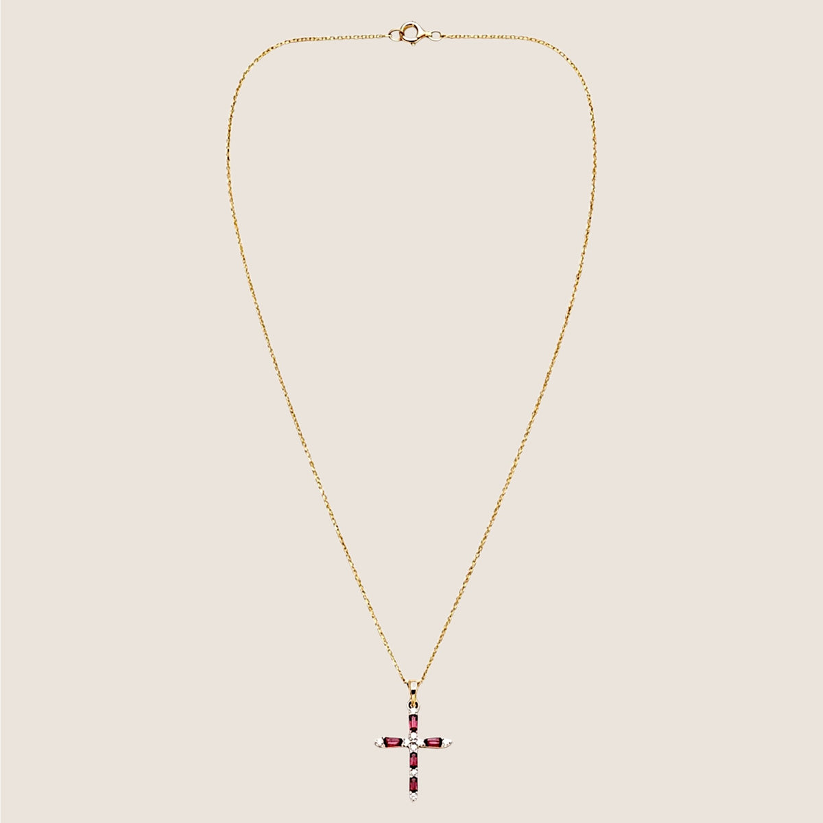 Entire ruby and diamond cross necklace laid flat, with the fine gold chain and spring-ring clasp visible