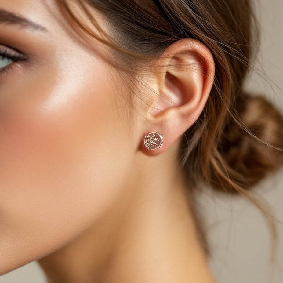Lifestyle photo of a model wearing the intricate silver love knot stud earrings to scale on her earlobe while elegantly holding her hand near her hair.