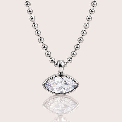 A silver beaded necklace with a marquise-cut clear gemstone pendant, displayed on a light beige background with a soft reflection below.