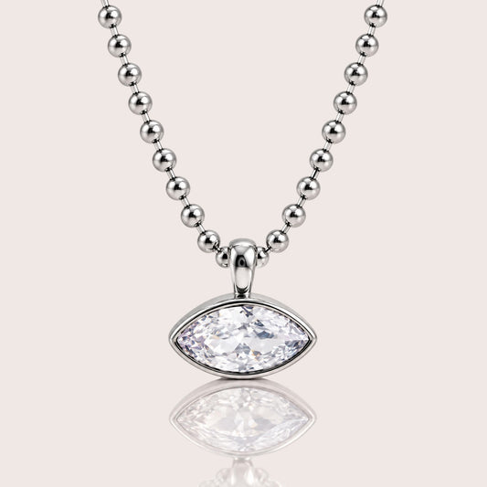 A silver beaded necklace with a marquise-cut clear gemstone pendant, displayed on a light beige background with a soft reflection below.