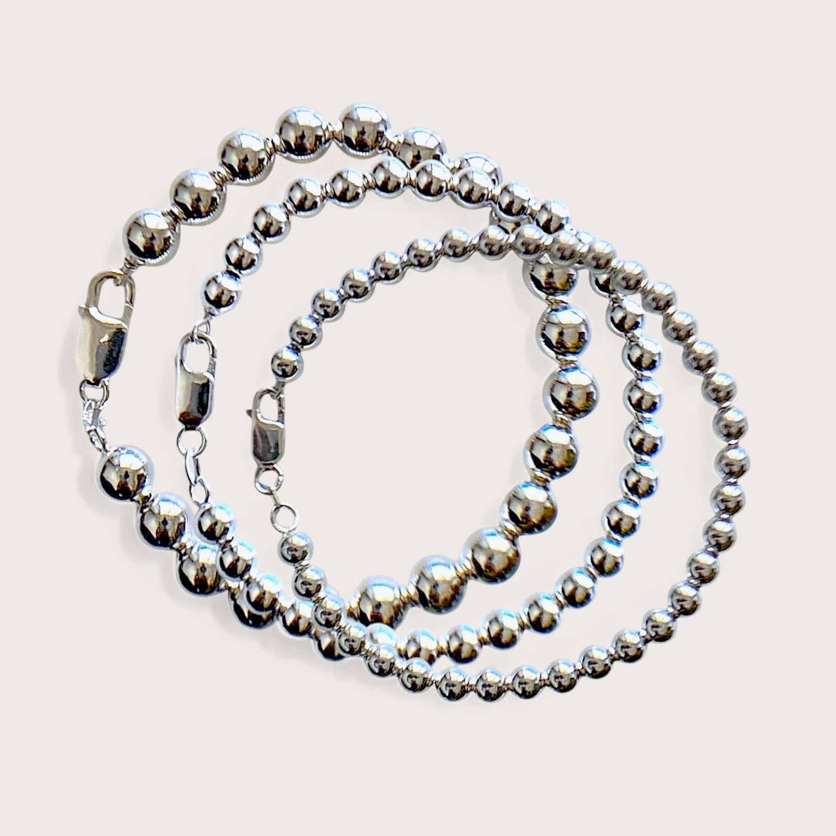 Close up of a polished 5mm 6mm, 8mm sterling silver ball bead bracelets with a large lobster claw clasp on a white background by Ashley Nicole Jewelry