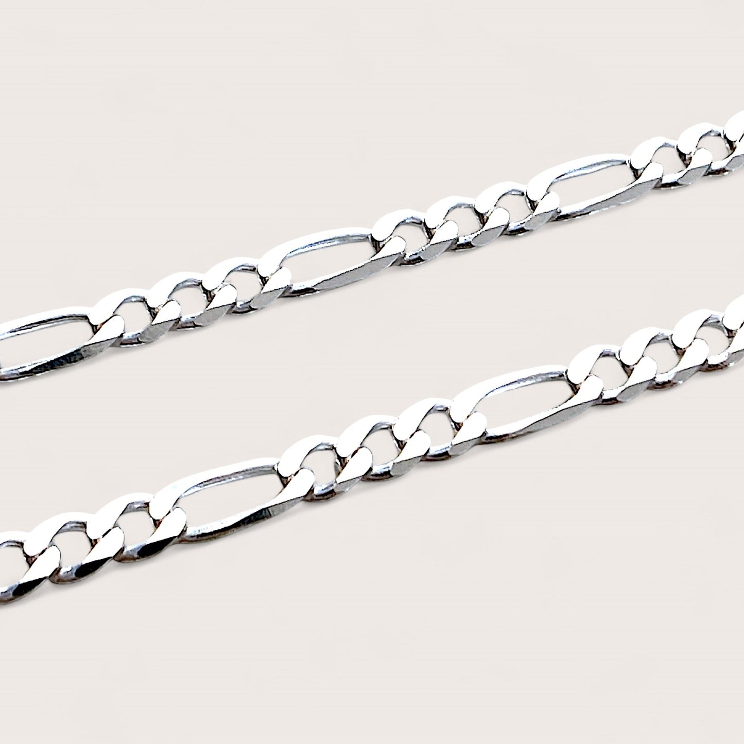 A detailed macro shot of the 4mm sterling silver Figaro bracelet link connectors and heavy-duty lobster claw clasp, highlighting the authentic Italian craftsmanship and brilliant polish.
