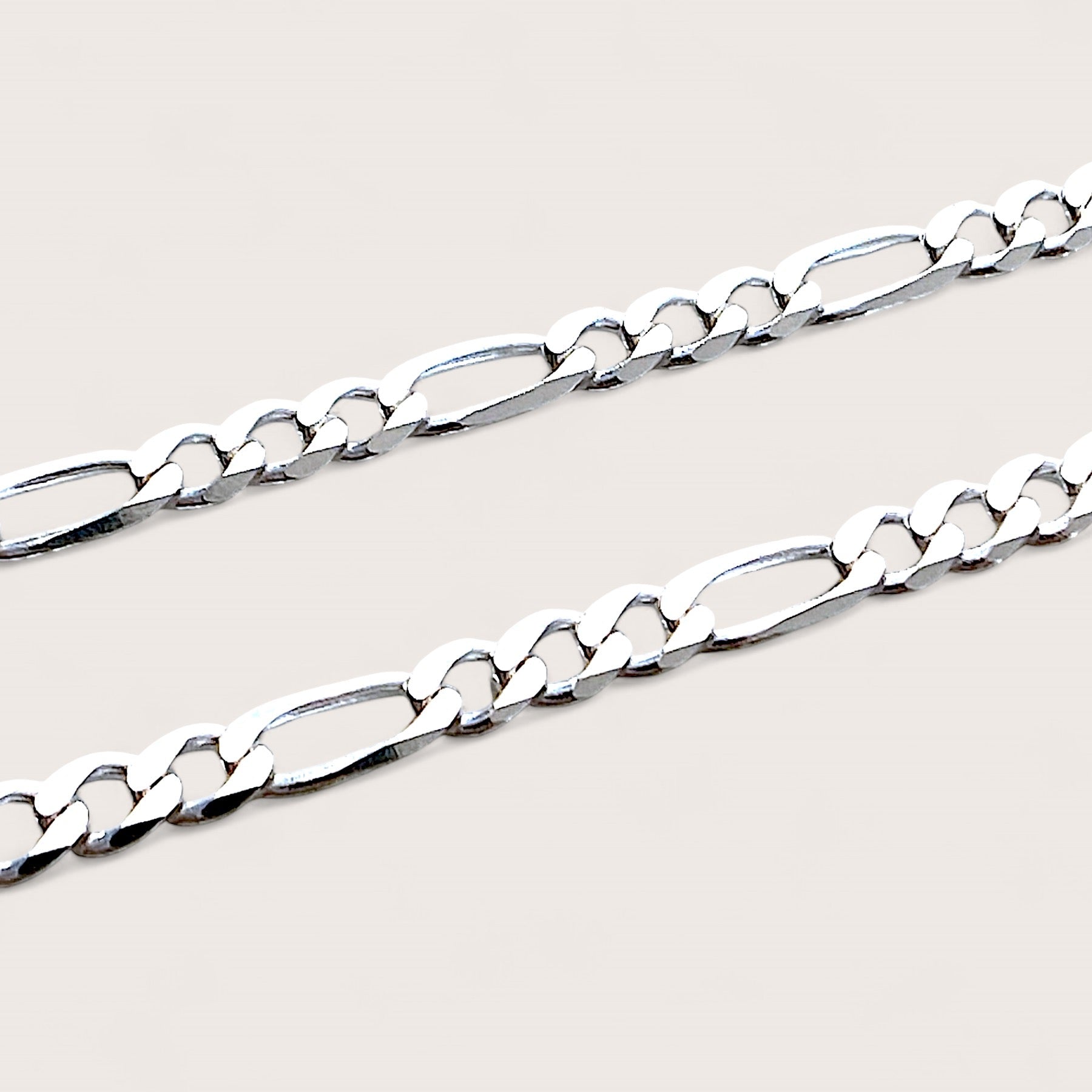 A detailed macro shot of the 4mm sterling silver Figaro bracelet link connectors and heavy-duty lobster claw clasp, highlighting the authentic Italian craftsmanship and brilliant polish.