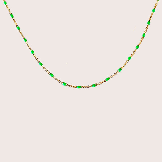 Gold Station Necklace with green beads evenly spaced on a beige background