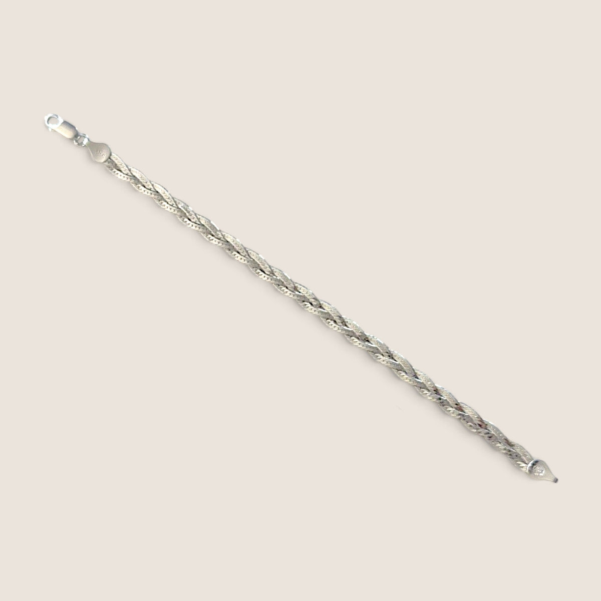 Sterling silver braided herringbone bracelet laid open diagonally with both clasp ends visible