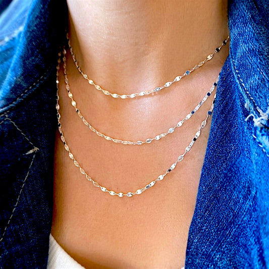 Three sterling silver mirror link necklaces layered with a blue denim shirt