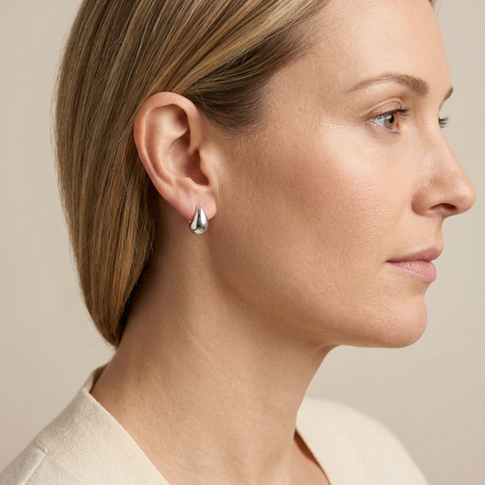 Woman wearing a petite sterling silver teardrop stud earring, shown in a side portrait