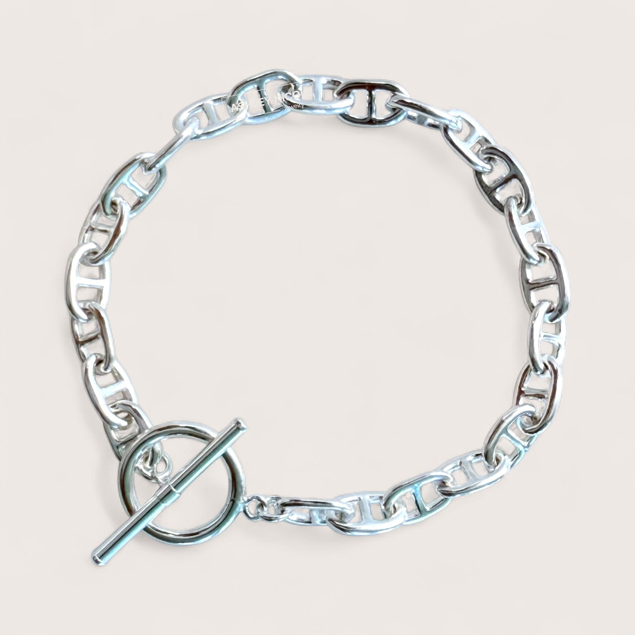 sterling silver anchor link bracelet with a toggle & bar clasp on a light beige background