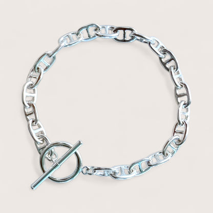 sterling silver anchor link bracelet with a toggle & bar clasp on a light beige background