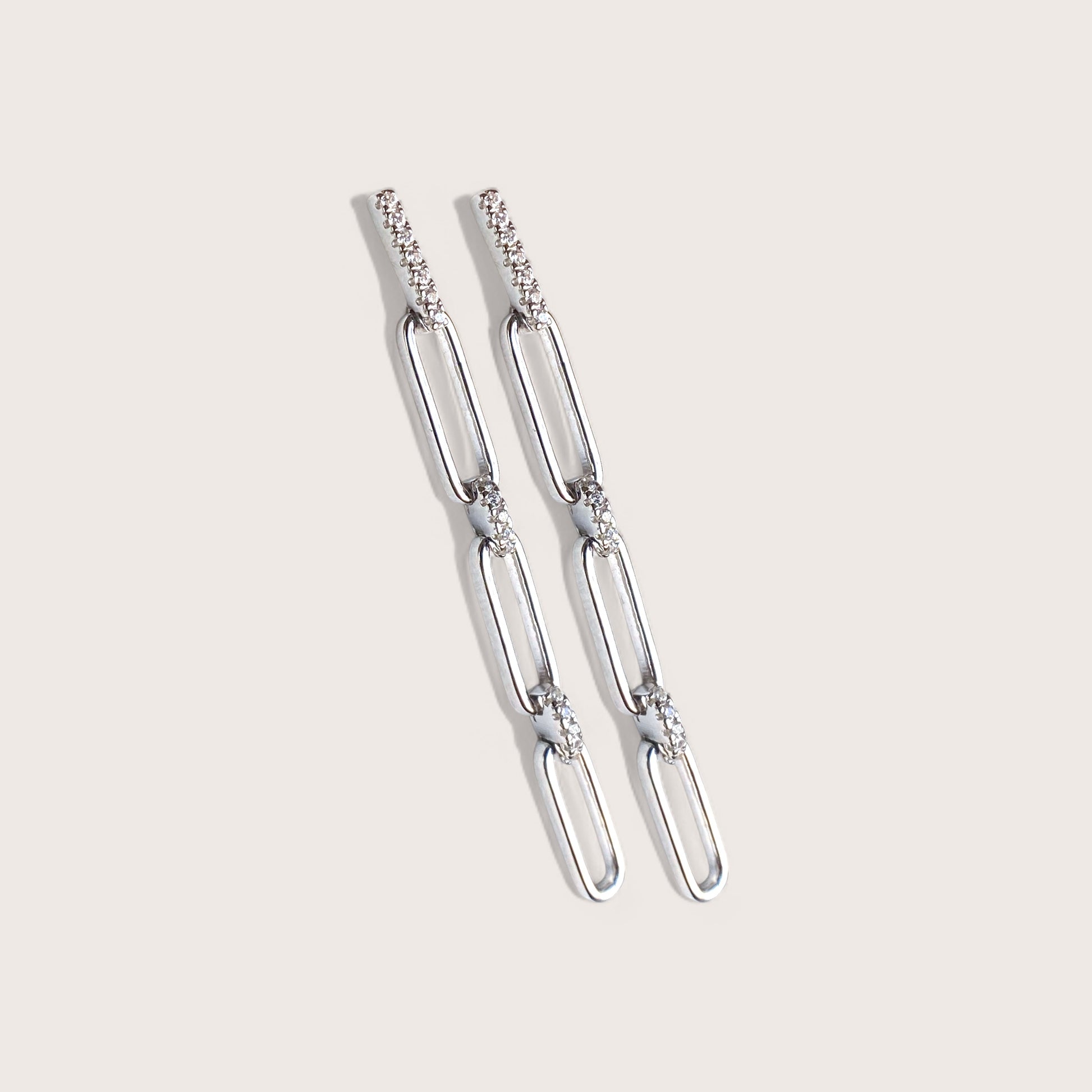 Close up of a pair of 925 sterling silver paperclip chain drop earrings with clear cz bar interlinks and post back studs