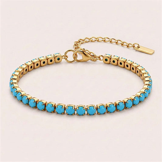 Turquoise-blue CZ tennis bracelet in gold prong settings, arranged in an oval with a lobster clasp and extension chain.