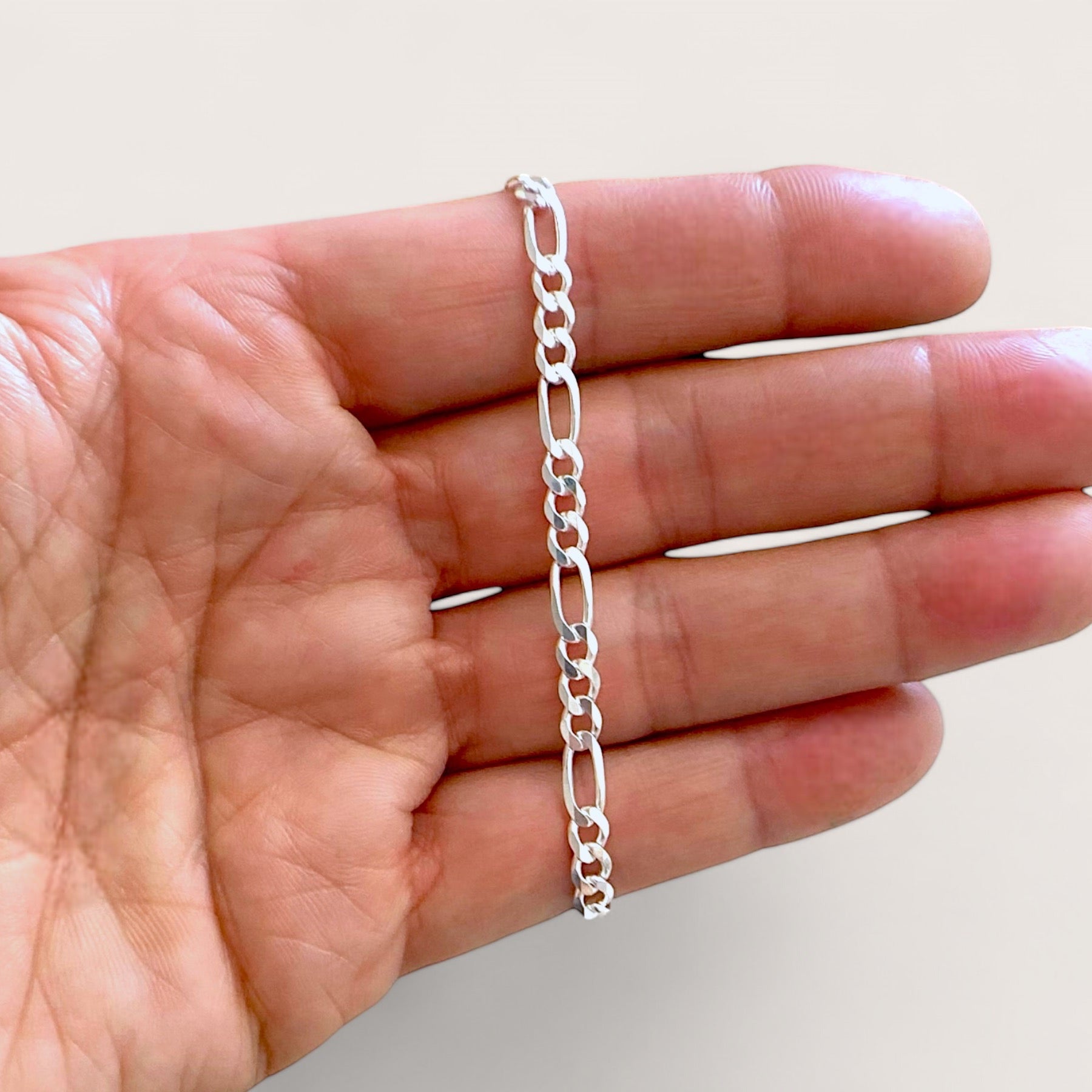 A close up shot of the 4mm sterling silver Figaro bracelet link connectors ahighlighting the authentic Italian craftsmanship and brilliant polish.