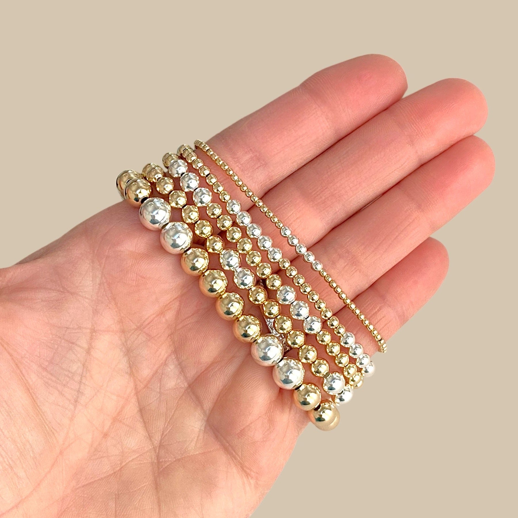 14K gold-filled and 925 sterling silver two-tone mixed metal beaded stretch bracelet showcased in a hand for size visual