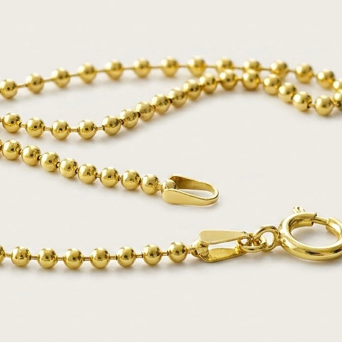 Close-up detail of a dainty gold 2mm gold-filled ball chain bracelet with a spring clasp showcasing the secure soldered ends.